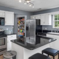 Gray kitchen with stainless steel appliances, white island with dark gray granite countertop, white cabinets - Jay Goslee Sells Middle TN